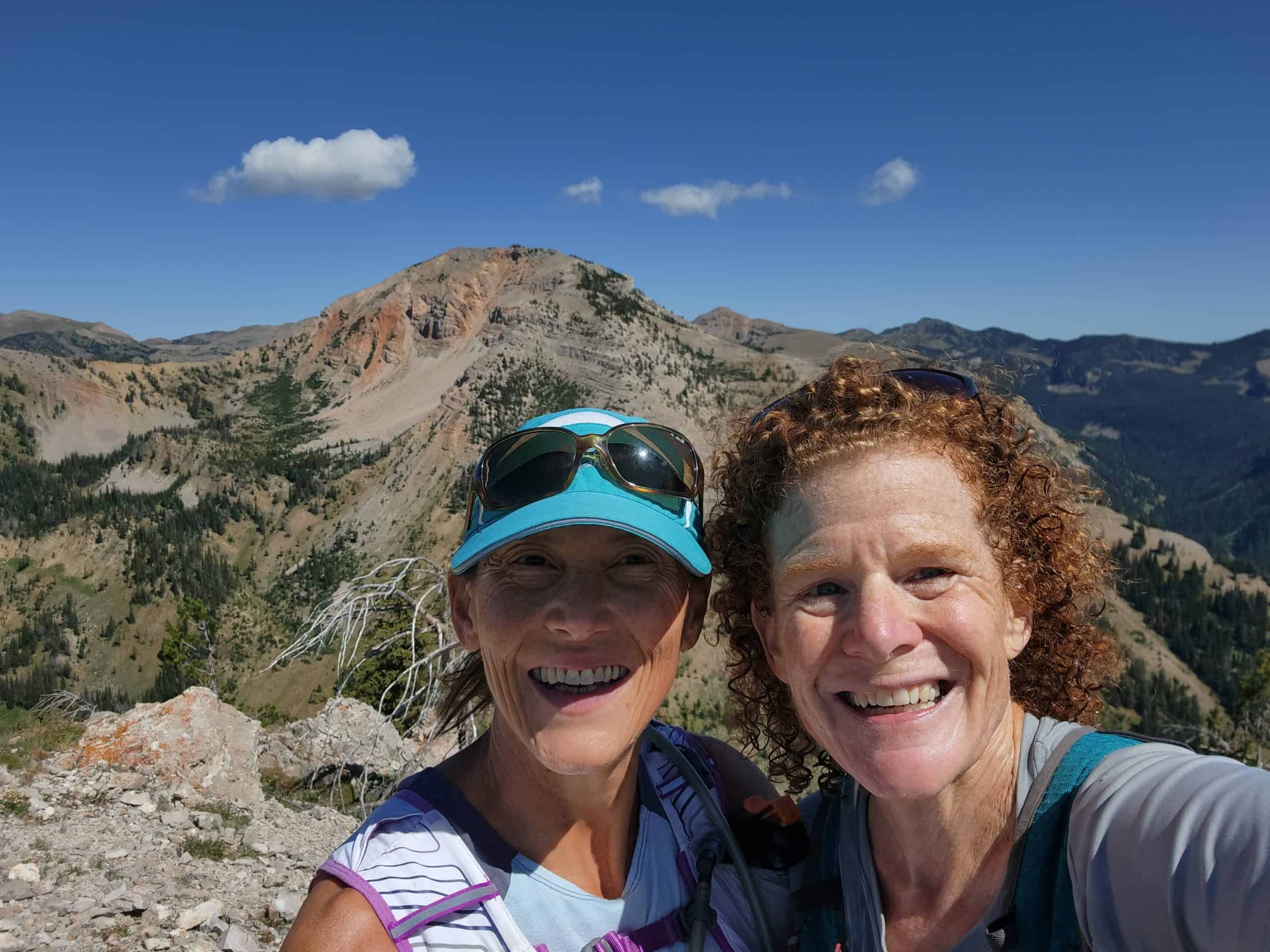 Founders Nikki Kimball and Kami Semick smiling together on a mountain summit